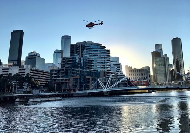 helicopter-flying-river-buildings-against-sky_1048944-27483099